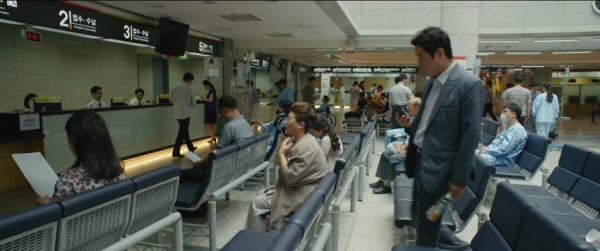 영화 기생충 내용 중 병원 수납 창구 앞에서의 문광(이정은)과 기택(송강호)의 모습